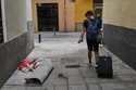 A tourist walks past a homeless woman in downtown Madrid, Spain, Tuesday, June 3, 2025