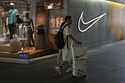 A man walks with his purchased goods as he shops at a Nike store outside a shopping mall in Beijing…